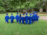 preschool graduates in cap and gown walking away